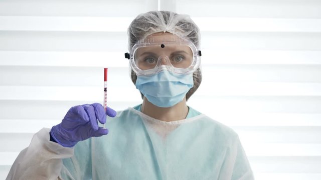 Portrait of a beautiful nurse in a protective suit with a syringe in her hands.
