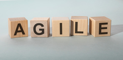 Wooden cubes spelling AGILE on grey background