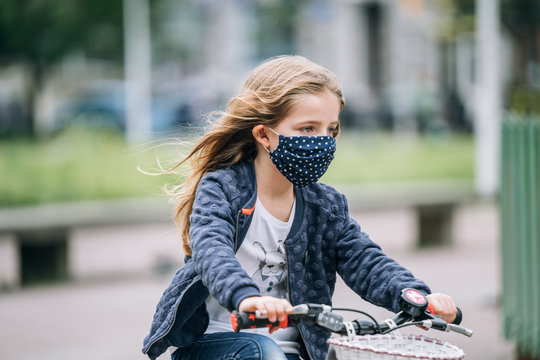 Little Girl Riding A Bike With A Face Mask