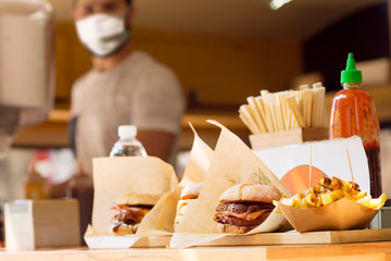 chef with mask for coronavirus prevention on food truck , selective focus in foreground