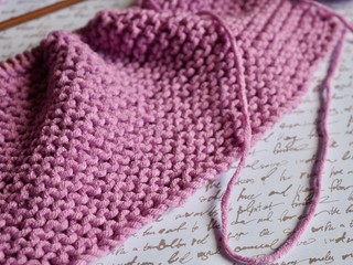 pink knitting on needles with calligraphy background 