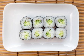 Kappa Maki classic roll with cucumber. Hosomaki thin rolls, simple rolls, small rolls, with cucumber. top view on a white plate.