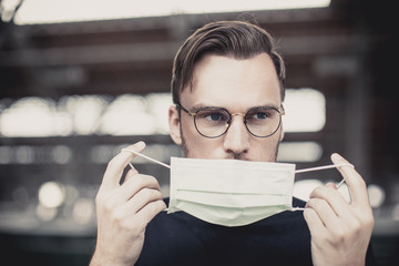 young attractive man with blue eyes and glasses puts on a breathing mask
