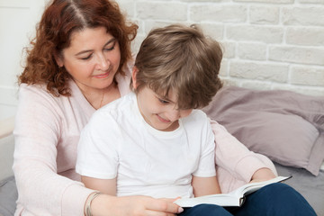 Beautiful Caucasian mom and son are reading a book.
