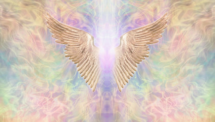 Golden Angel Wings Banner - Wide wispy multicoloured ethereal background with a pair of golden Angel Wings in the centre with a shaft of bright light between and  copy space both sides
