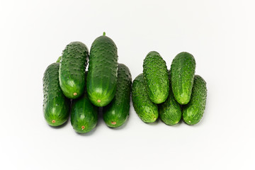 Cucumbers on white background. Two stacks of fresh green variety sizes cucumbers. Close up.