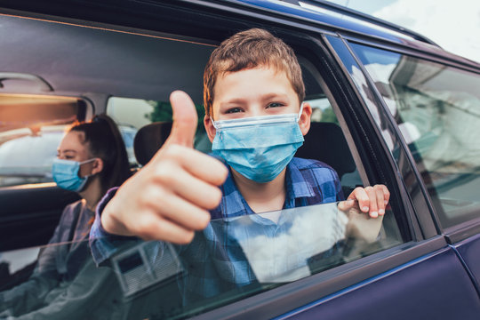 Kids wearing anti virus masks and using digital tablets in the car. Kids are travelling in car during coronavirus outbreak