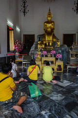 Buda dorado del templo de Wat Pho en Bangkok con personas rezando