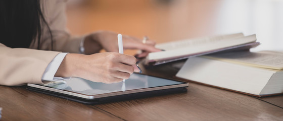 Woman at work reading and writing with tablet on the desk.