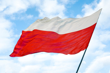 Fototapeta na wymiar Polish red and white flag against a blue sky, state flag day on may 2 on a Sunny day. May 2, November 11, flag, independence or labor Day.