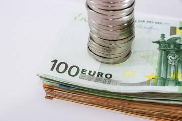 stack of coins on a stack of euro banknotes. Close-up.