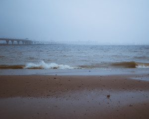 beach in the morning with fog and bridge