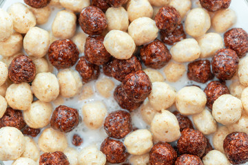 Breakfast cereal white chocolate balls close-up selective focus in milk background, texture