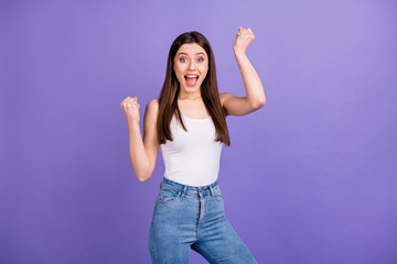 Obraz na płótnie Canvas Photo of pretty attractive lady open mouth raise fists listen amazing news celebrating victory wear white singlet blue jeans isolated pastel purple color background