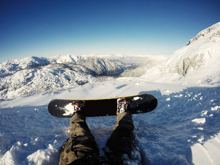Closeup of snowboarder legs, ready for downhill run. Beautiful winter Alpine landscape in Dachstein...