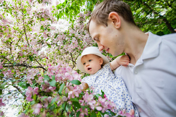 Obraz premium Happy family in the spring garden. Father and little daughter together in a blooming Sakura Park.