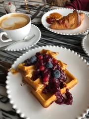 French breakfast at the restaurant or cafe with croissant with jam, coffee, waffle with berries and dessert on marble table. Gourmet food. Sweets. French pastry. Bakery.