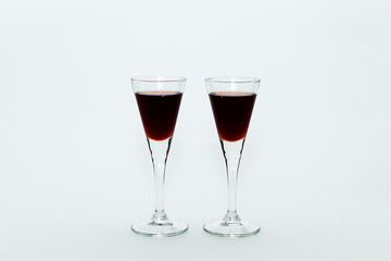 Two small glasses with red wine on a white background