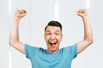 man showing thumbs up and smiling, rejoices in victory, in blue shirt