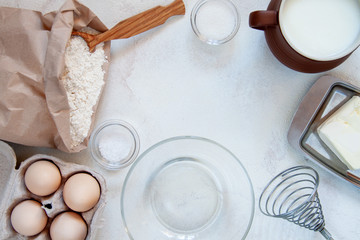 Ingredients for making dough for homemade pancakes for breakfast. On the table are wheat flour, eggs, butter, sugar, salt, milk. Selective focus. Sequencing