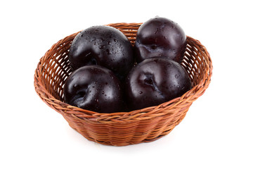 Black plums on wicker plate