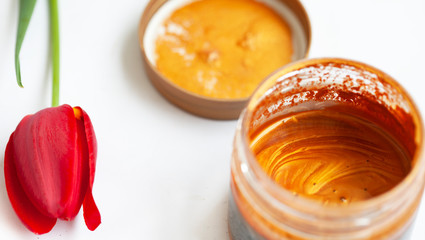 Jar with cream and flowers on wooden background. Skin care cosmetics