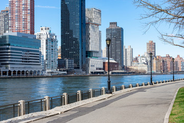 Naklejka premium Empty Waterfront along the East River at Roosevelt Island and looking towards the Upper East Side Skyline of New York City during Spring