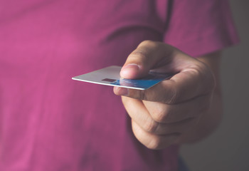 A girl handing a credit card to a person standing in front, buying goods through a credit card, paying off debt, the concept of spending money without cash