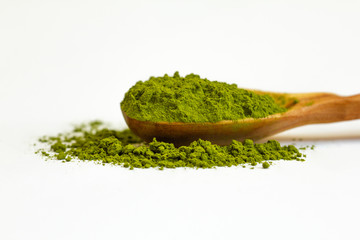 Green tea matcha in a wooden spoon on a white background close-up. Dry green tea. Macro of a matcha. Side view.
