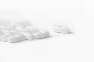 White pills on a white background close-up. Painkillers. A remedy for the Covid19 virus. Tablet macro. Copy space.