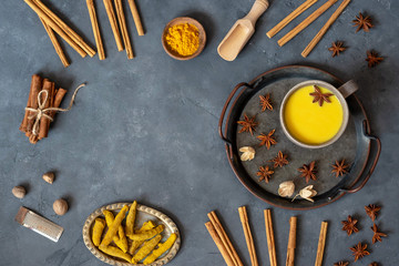 Traditional indian golden milk drink with turmeric, cinnamon on wooden background. Copy space.