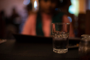 Glass half filled with drinking water on the table of a restaurant. Indian cafe