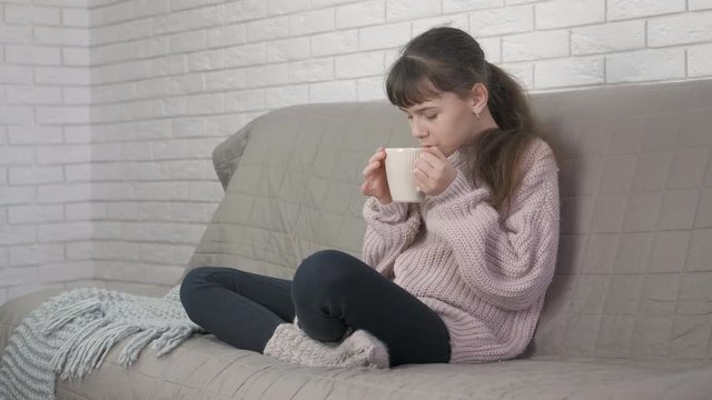 Girl in warm clothes with a cup of tea.