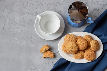 Oatmeal cookies with a coffee pot and a white cup. View from above. Gray concrete background.