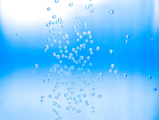 Naklejka na ściany i meble Close-up water drops in water bottle against to blue background