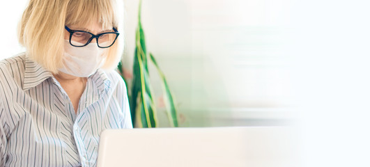 Banner with adult serious blonde woman in glasses and face mask using laptop in workplace at home. Remote learning. Social distancing protect coronavirus or covid-19. Online education and work concept