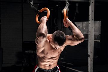 Athlete does warm-up on gymnastic rings. The concept of sport and healthy lifestyle.