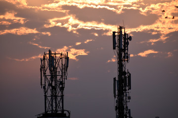 Naklejka premium Sunrise behind mobile tower in the city
