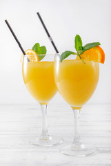 glasses of orange juice with mint and cocktail tubes on a white background, cocktail, close up