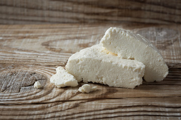 homemade Adyghe cheese cut into pieces on a wooden background