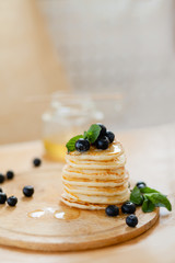 A stack of Golden pancakes drizzled with honey and garnished with blueberries and mint
