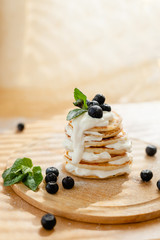 Golden pancakes with sour cream and blueberries in the morning sun