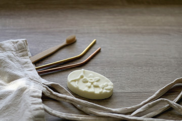 Canvas tote bag with zero waste products: bamboo toothbrush, reusable metal straws and soap. Selective focus.