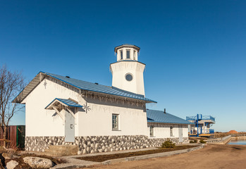White building with a blue roof and a small lighthouse. The building is decorated with a Christmas garland. Bright sunny day