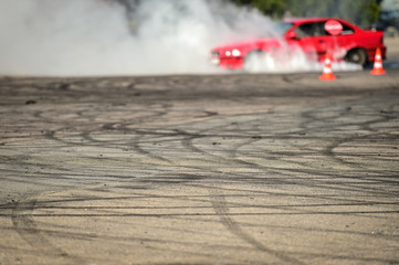 Rubber drift traces and traffic cones inside a driving school polygon. Car drifting in the background. © roibu