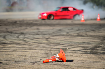 Rubber drift traces and traffic cones inside a driving school polygon. Car drifting in the background. © roibu
