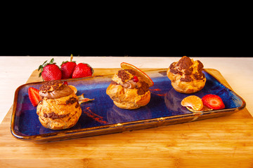 profiteroles decorated with strawberries on a plate in the studio