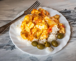 Hearty breakfast with rice and meat in a white plate, serving on a black and white paper napkin