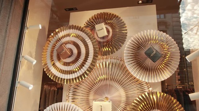 stylish gold-colored handbags and clutches on window of an expensive Italian store, decor elements are spinning to attract the attention of shopping buyer