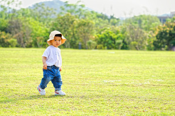 The little boy in a hat in the outdoor lawn
